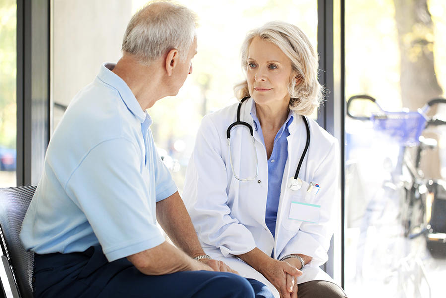 Older male patient sitting and talking with female doctor