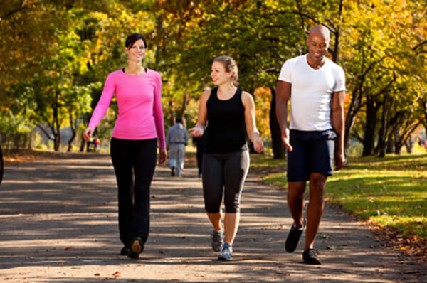 Two women and one man walking outside.