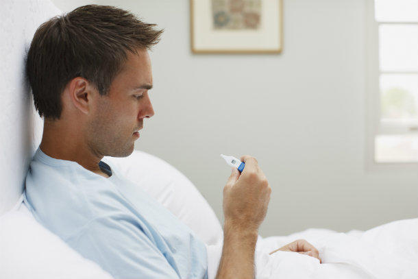 Cancer patient using a thermometer to check his temperature.