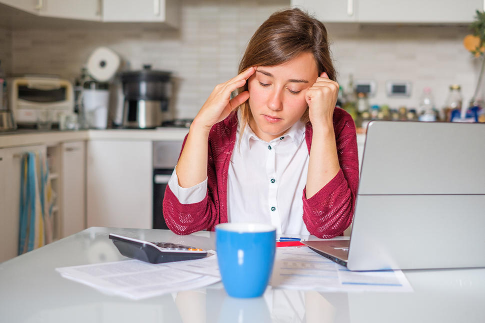 Worried woman sitting at kitchen table.