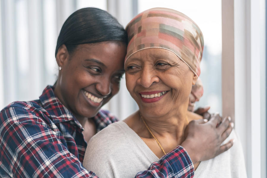 Hija afroamericana abrazando a su madre y sonriendo