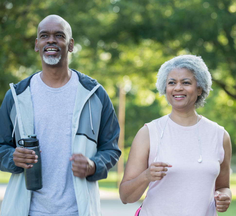 An older African American couple walking in a park.