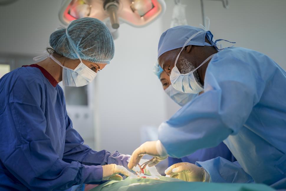 Photo of doctors performing surgery in a hospital operating room.