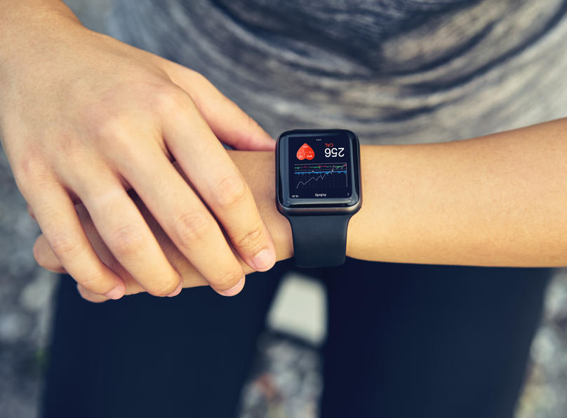 A young woman checks her heart rate on a smartwatch wearable device.