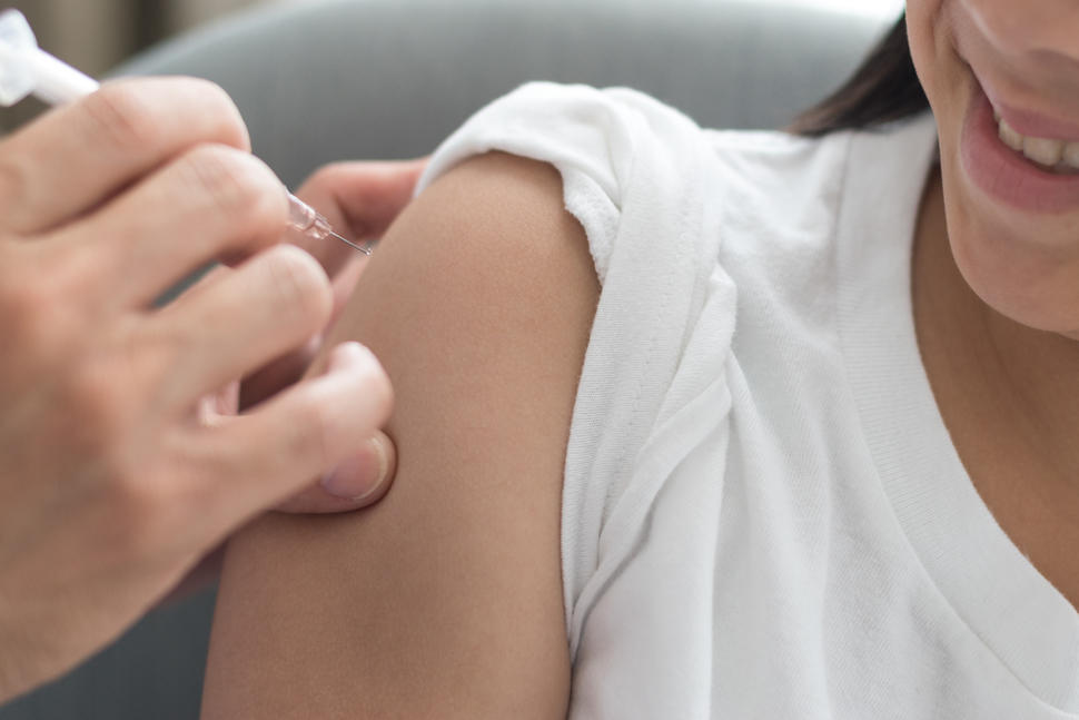 Photo of a girl being injected with a vaccine in her upper arm.