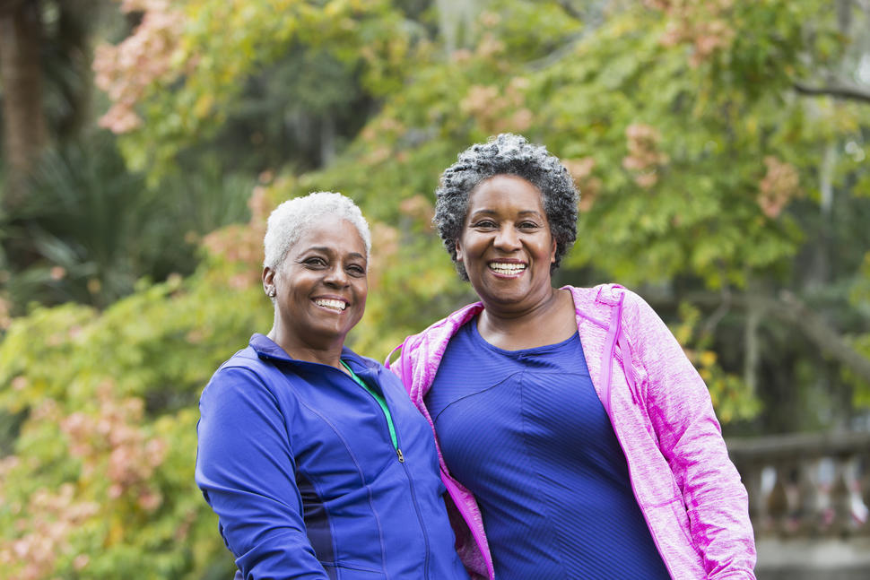 2 middle-aged women in a park pose for the camera