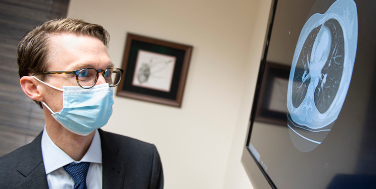 Image of Robert Vanharen wearing a mask looking at screen with scan image