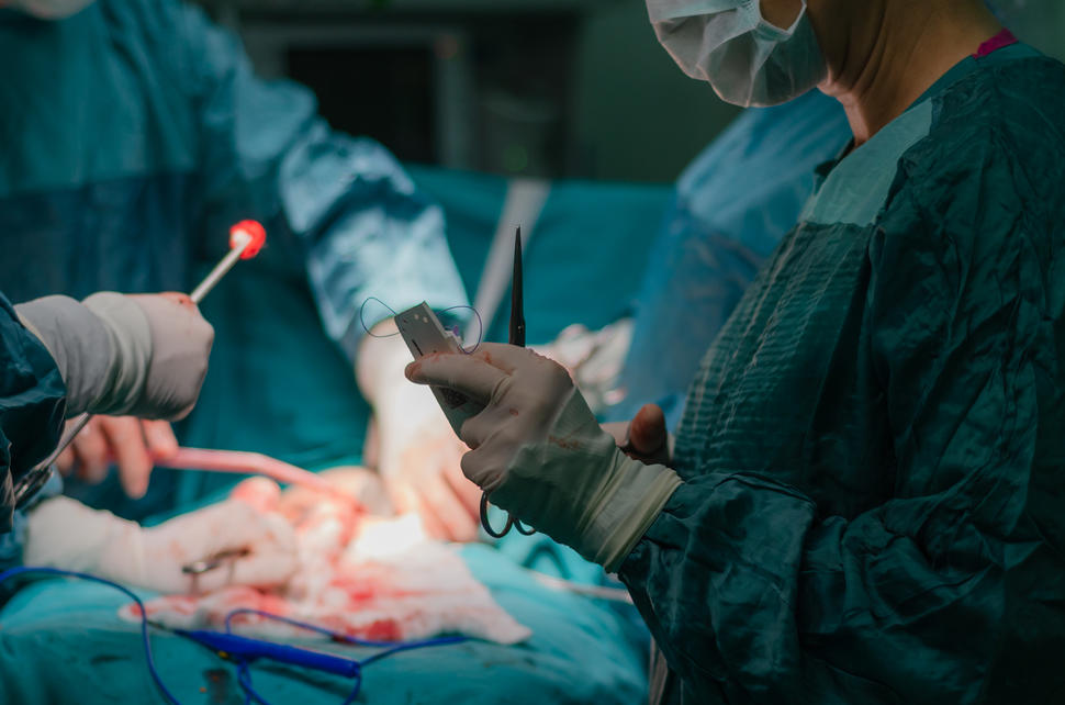 A surgical team standing over a patient in the operating room.