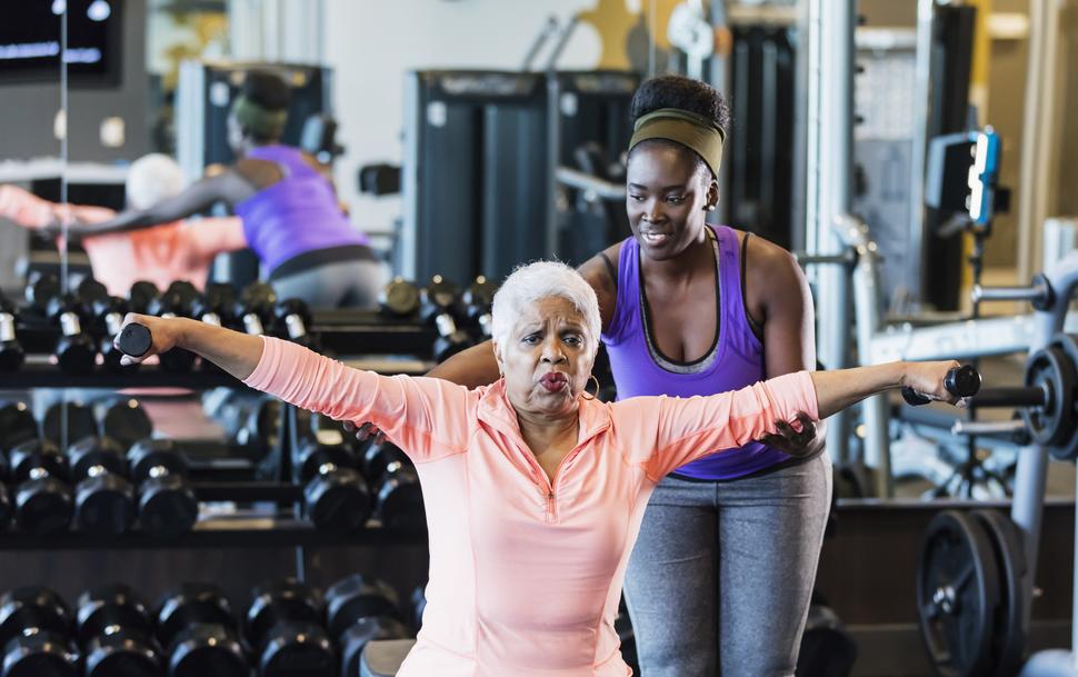 Older African-American woman lifting weights in a gym