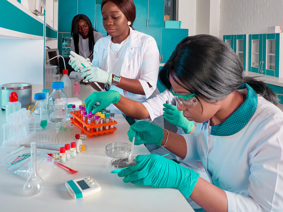 Three female African scientists working in research laboratory, testing various substances