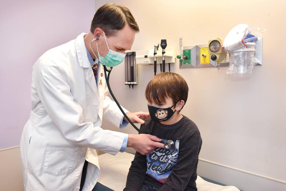 Image of a physician, Dr. Matthew Kutny, using a stethoscope to examine a child named Asher.