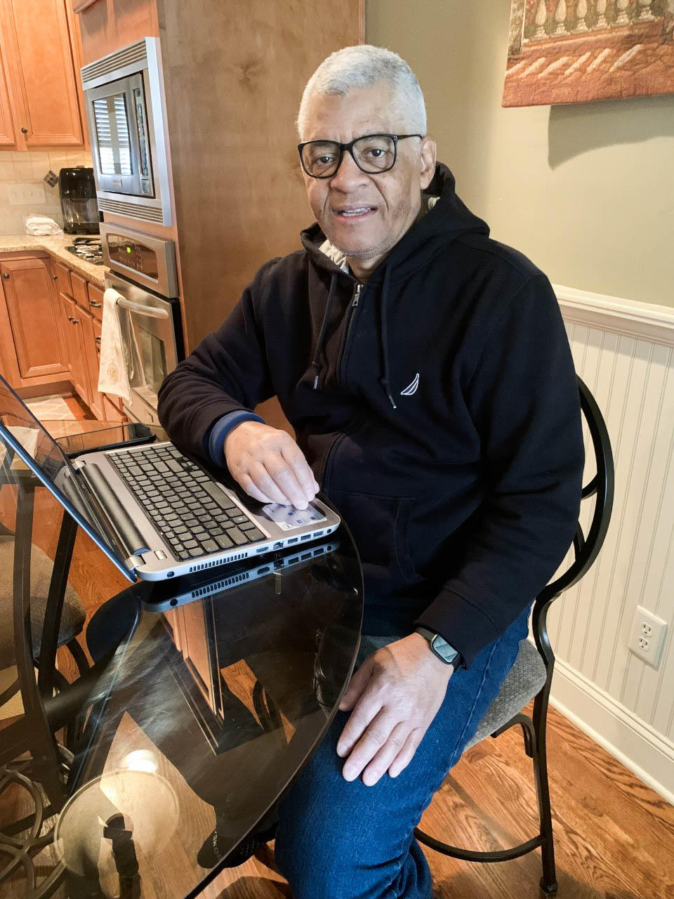 Larry Starling sentado en la mesa de su cocina con una computadora portatil abierta