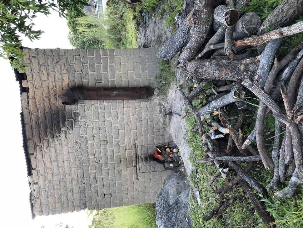 Photo of shed used to cure tobacco with fire underneath and burn marks on side.