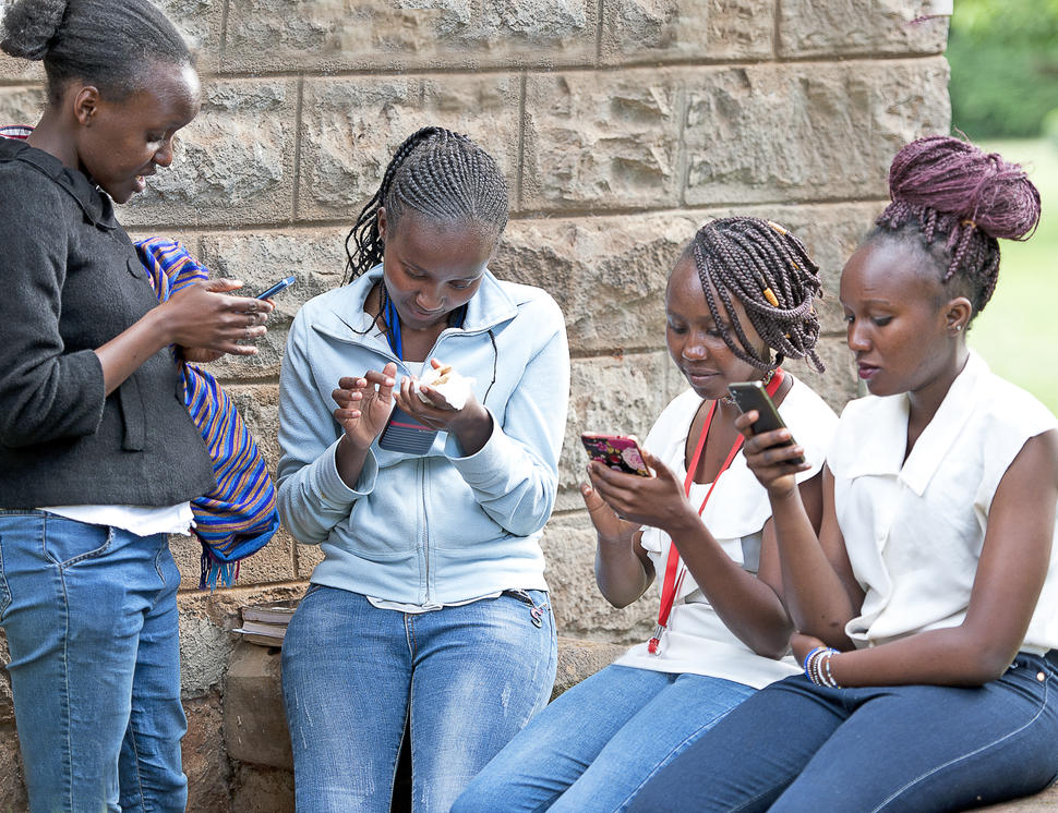 Cuatro adolescentes kenianas mirando su teléfono celular