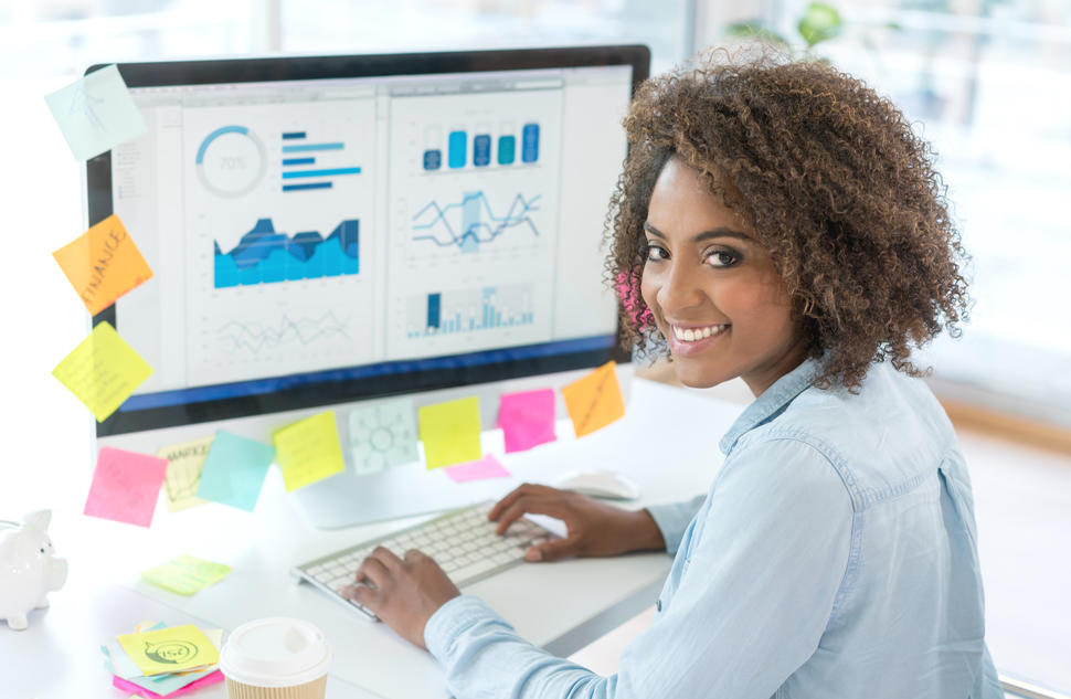 Creative business woman working at the office on the computer and looking at the camera smiling