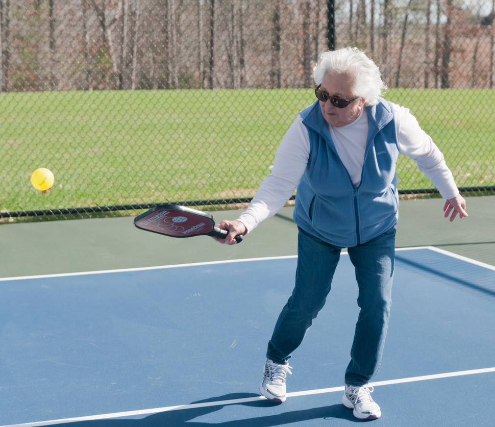 Image of an older woman playing pickleball. 
