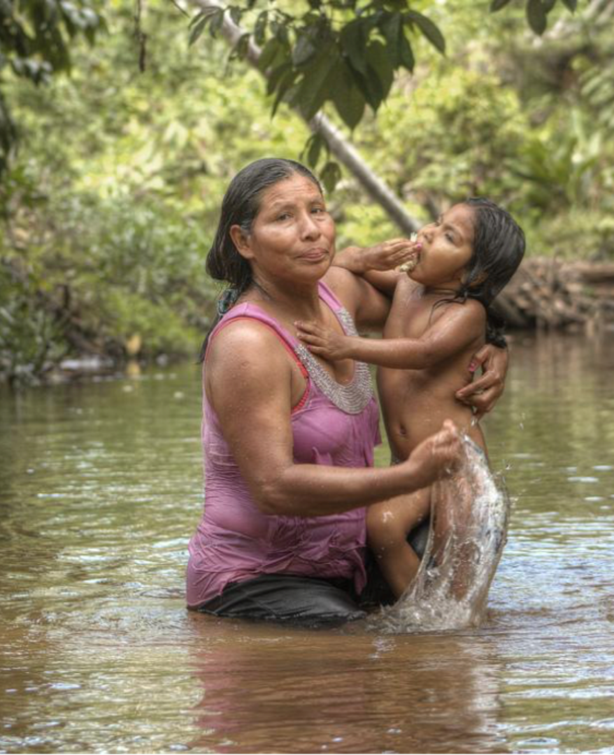 Woman bathing her daughter in a river in Peru