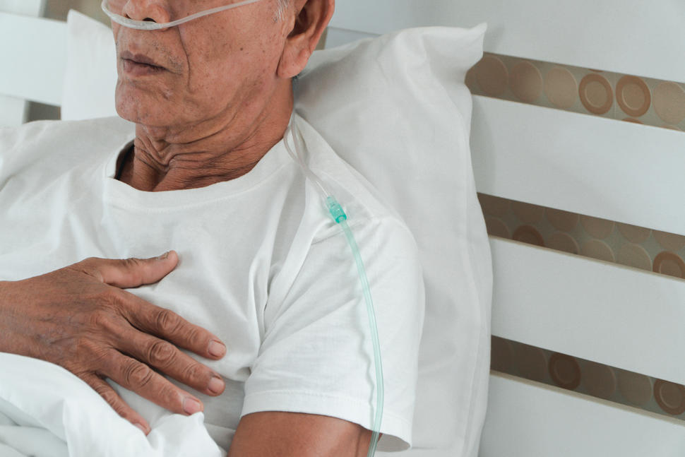 A photo of an older man in a hospital bed with a canula in his nose.