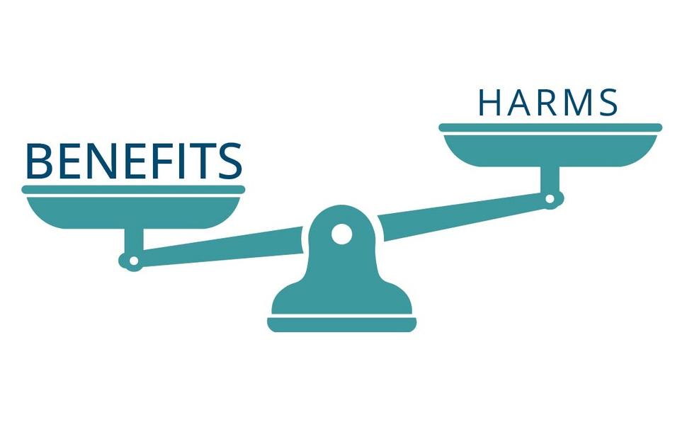 Illustration of a set of scales with the word "benefits" outweighing the word "harms"