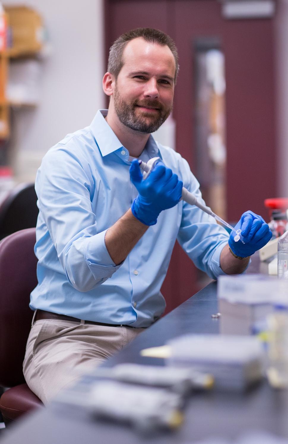 Photo of Dr. Kevin Janes in his laboratory holding a pipet