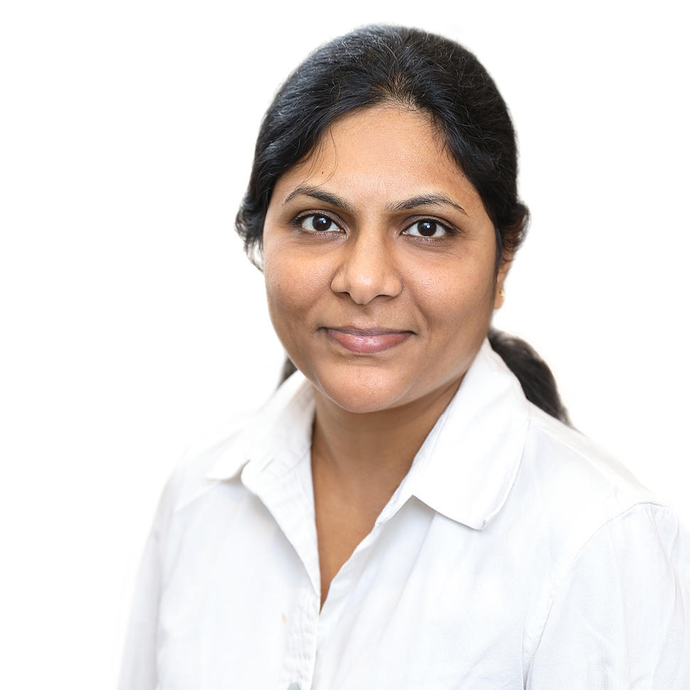 Headshot of Indian woman (Dr. Subhashini Jagu) with hair tied back in a ponytail, wearing a white shirt in front of a white background.