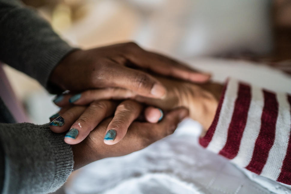 A pair of hands clasping the hands of another person.