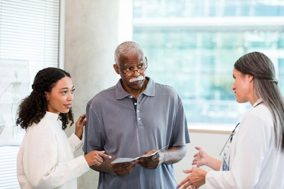 An older man and his adult daughter talking with a female doctor