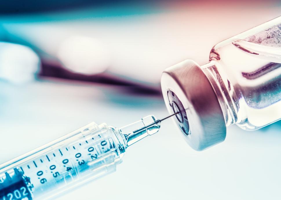 A syringe withdrawing liquid from a glass vial