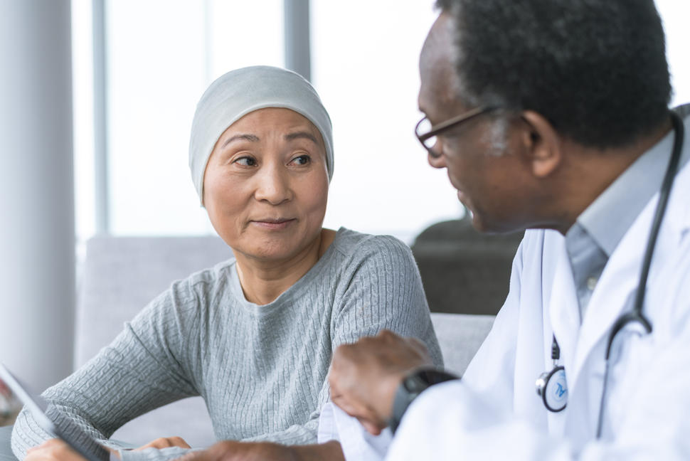 Photo of a woman in head covering sitting and meeting with her doctor.