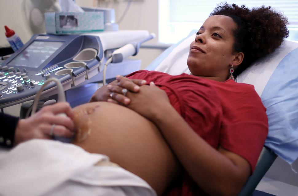 A young pregnant woman undergoing an ultrasound in the doctor's office