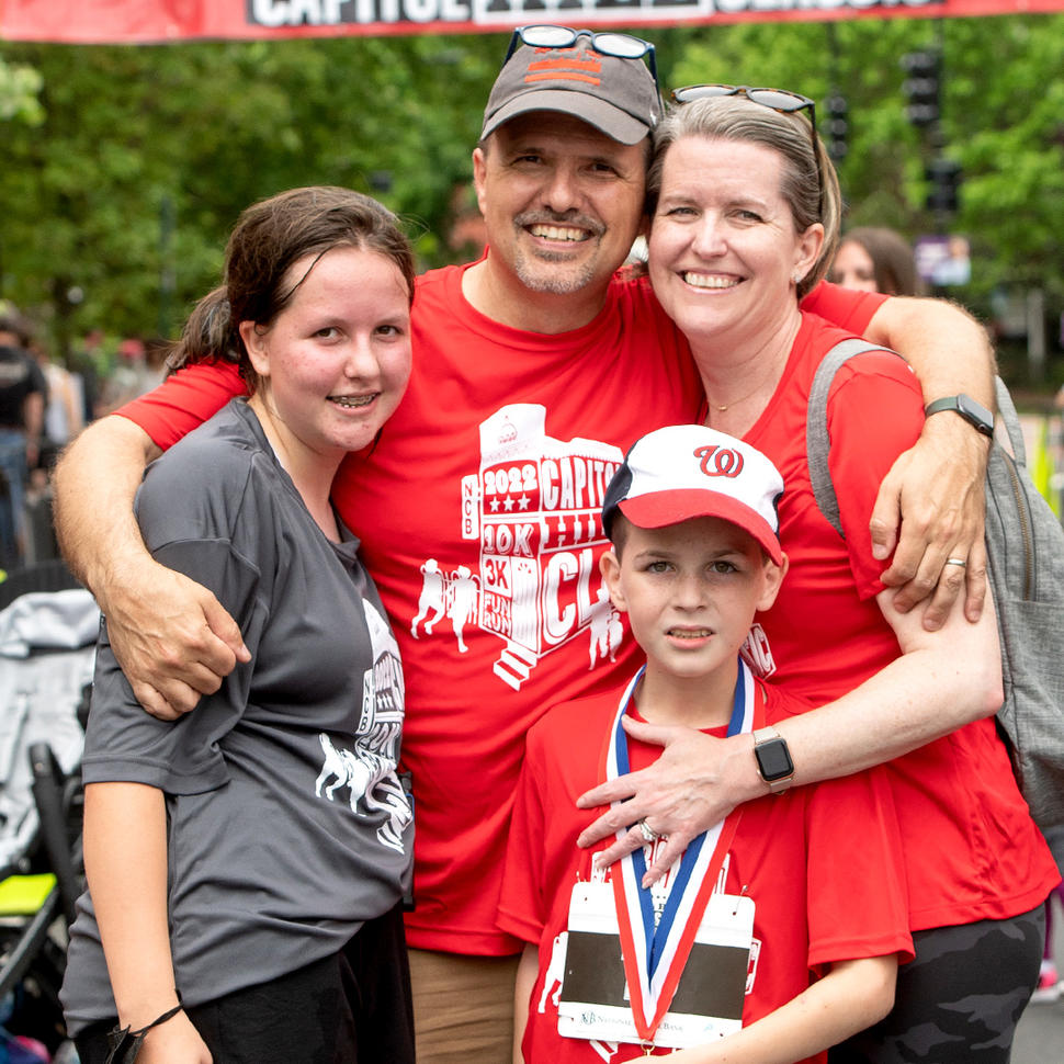 Jason Levine standing with his wife, daughter, and son at the finish line of a race.