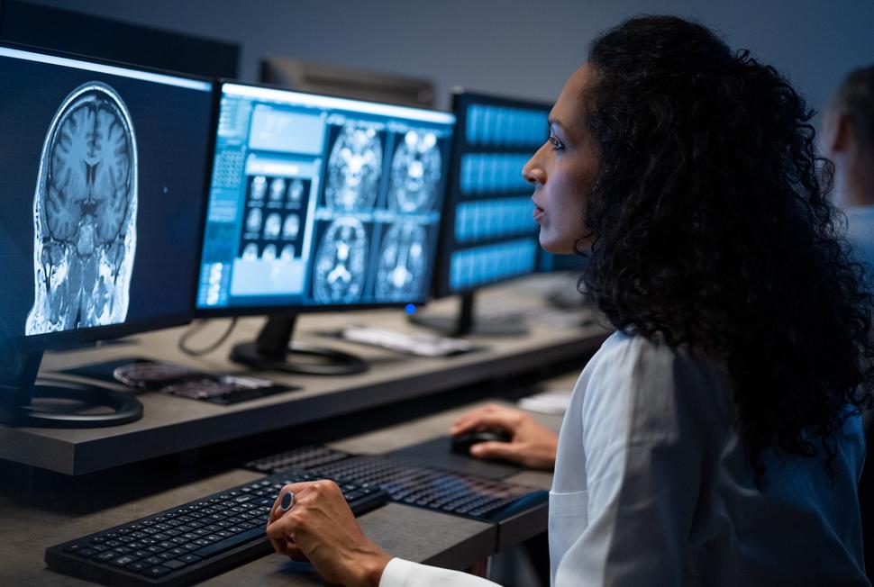 A radiation technologist analyzes brain MRI images on a computer screen