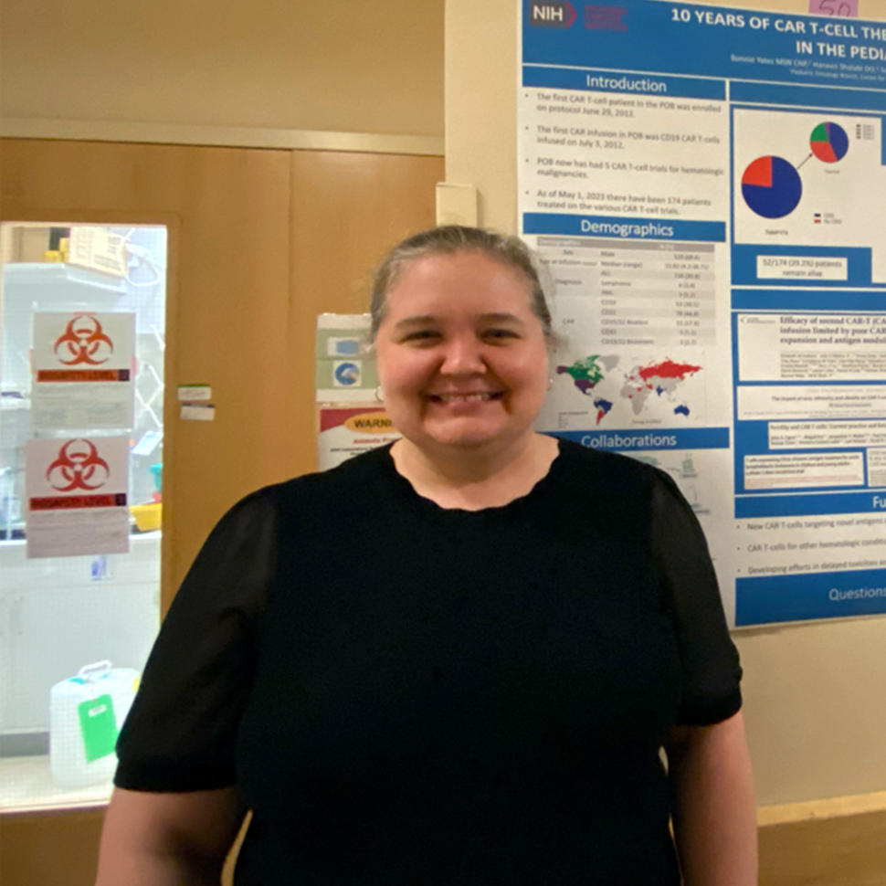 Bonnie Yates standing in a hallway with scientific data and graphs posted on the wall in the background.