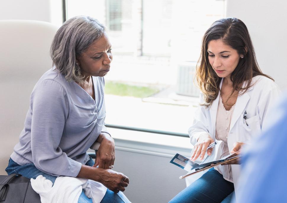 A young female doctor talking with an older female patient