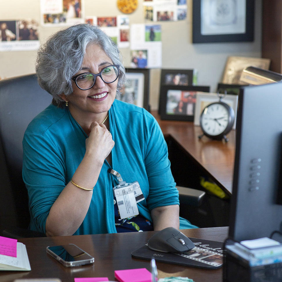 A woman, Dr. Smita Bhatia, sits in her office looking at her computer.