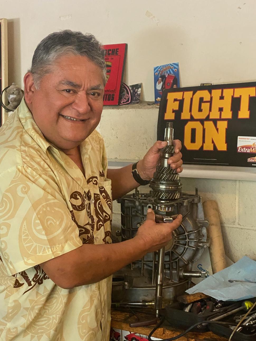 A picture of Adan Reinosa in his garage with a piece of a car engine.