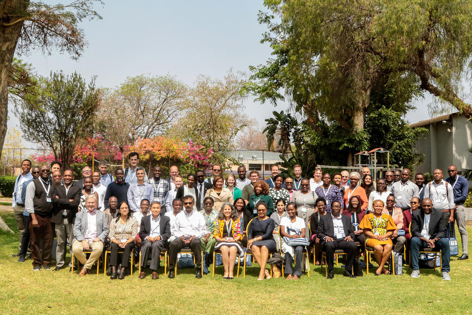 A group photo of approximately 60 participants at the U54 Consortia Annual Meeting. The photo is outdoors with the front row seated on chairs and two rows of people behind them.