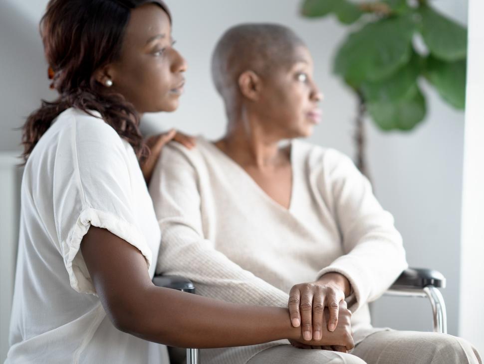 A daughter sits next to her mother, who's in a wheelchair