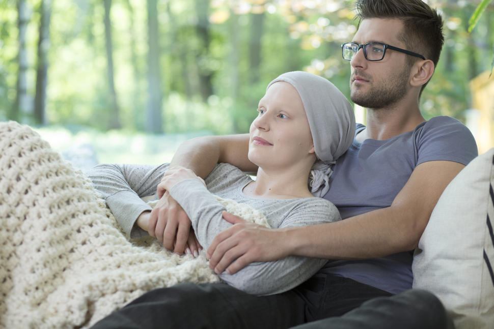 Sick woman lying in man's arms relaxing on couch.
