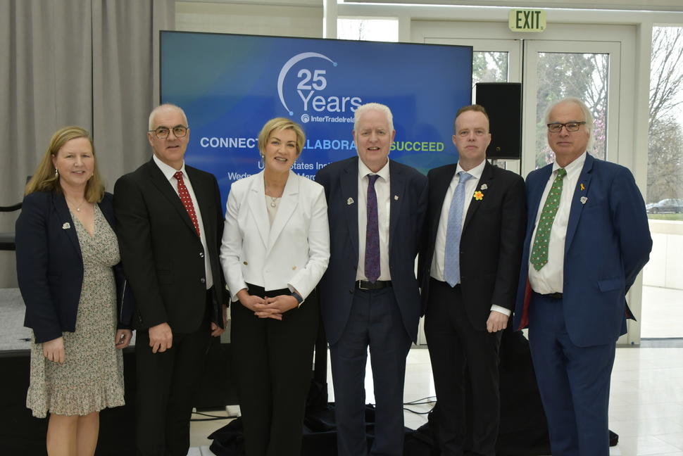 image of people standing in front of a banner advertising the 25th anniversary of the Ireland, Northern Ireland, National Cancer Institute Cancer Consortium. 