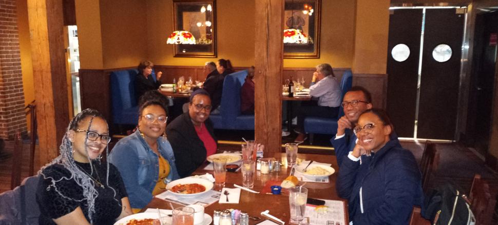 Group of BlacK researchers at restuarant table with five women and one man