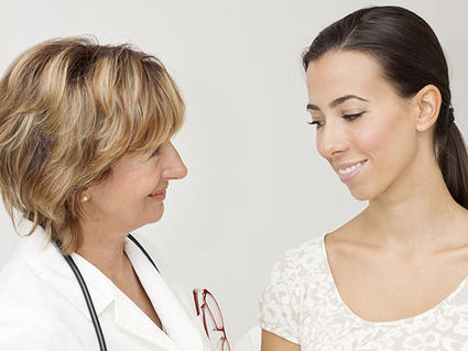 Female doctor talking with an appreciative, young female cancer patient.