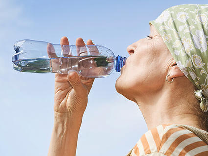 A woman is drinking a full bottle full of water to stay hydrated 