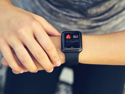 A young woman checks her heart rate on a smartwatch wearable device.