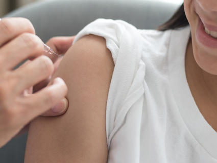 Photo of a girl being injected with a vaccine in her upper arm.