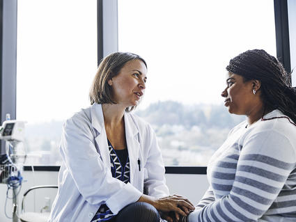 Female doctor speaks caringly to Black female patient 