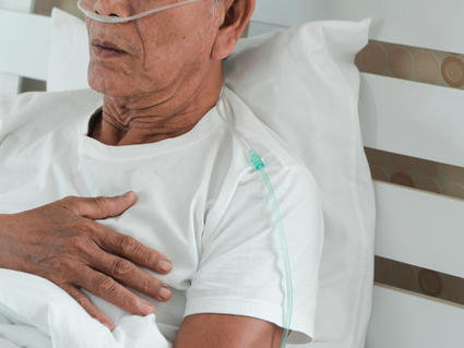 Un hombre mayor acostado en la cama con una cánula nasal.