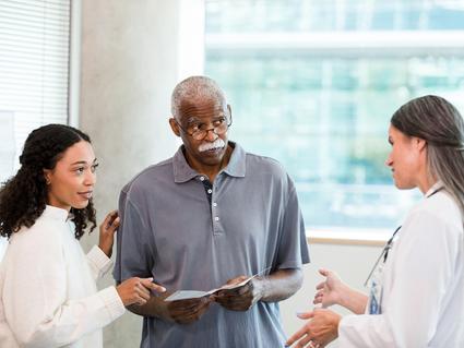 An older man and his adult daughter talking with a female doctor