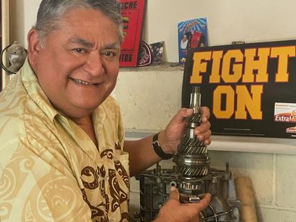 A picture of Adan Reinosa in his garage with a piece of a car engine.