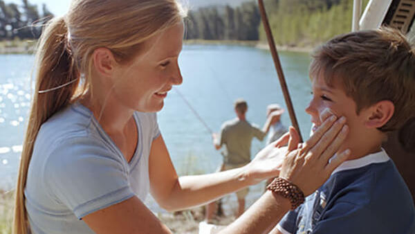 mother applying sun screen on child's face